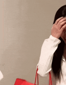 a woman in a white shirt is covering her face with her hands