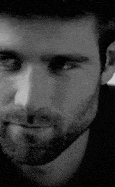 a close up of a man 's face with a beard in a black and white photo