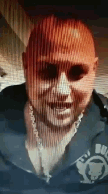 a man wearing sunglasses and a chain around his neck is smiling in a blurry photo .