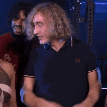 a man with curly blonde hair is giving a thumbs up sign