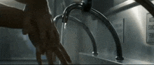 a person washing their hands under a faucet with a sign that says auto stand front