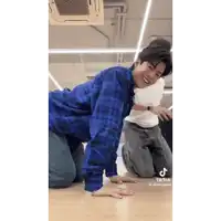 a man in a blue plaid shirt is kneeling on the floor with his hands on the floor .