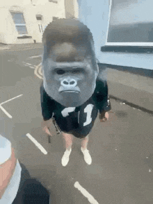 a person wearing a gorilla mask and a number 1 shirt is walking down the street .