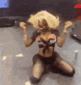 a woman is kneeling down on the floor with her arms in the air .