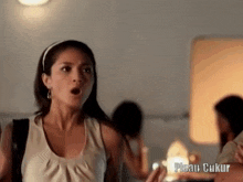a woman with a surprised look on her face is standing in front of a sign that says pisau cukur