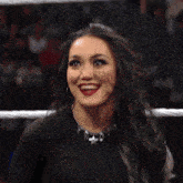 a woman with long black hair is smiling while standing in a ring .