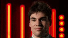 a man in a green shirt stands in front of a row of red lights