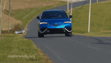 a blue acura is driving down a road with motorweek.org written on the bottom