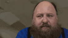 a bald man with a beard is wearing a blue shirt and says perfecto