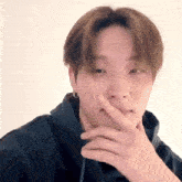 a young man is covering his mouth with his hand and making a funny face .