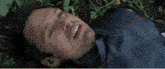 a man in a blue jacket is laying on the ground