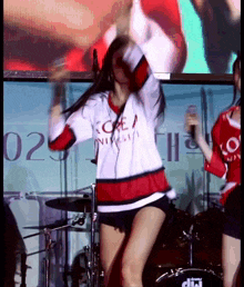 a girl wearing a korea university shirt is dancing on stage