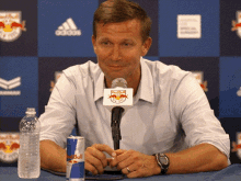 a man sitting at a table with a can of red bull