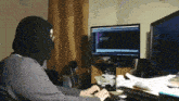 a person wearing a mask is typing on a keyboard in front of a computer monitor