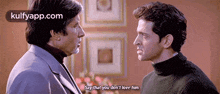 two men are standing next to each other in a room and one of them is saying that he does n't love him .