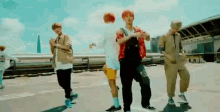 a group of young men are dancing on a street in front of a building .
