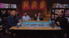 a group of people sitting around a table with nrb written on a wall behind them