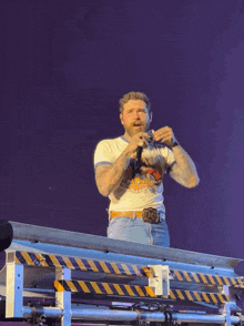 a man singing into a microphone on a stage with a purple background