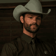 a man with a beard wears a cowboy hat and tie