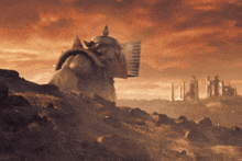 a statue of a man standing on top of a hill with a red sky in the background