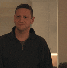 a man in a black jacket is smiling and looking to the side