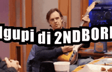 a man is playing a guitar in front of a sign that says ' i gupi di 2ndbor '