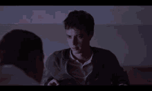 a man in a gray jacket is talking to another man