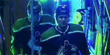 a hockey player wearing a helmet with the number 57 on it stands next to another hockey player .