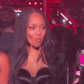a woman in a black dress is making a funny face with her eyes closed in a dark room .