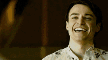 a young man in a floral shirt is laughing .