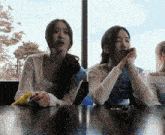 two girls sitting at a table with one wearing a shirt that says ' sounds ' on it