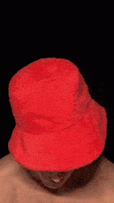 a man without a shirt is wearing a red hat .