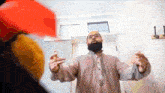 a man with a beard is standing in front of a door with his arms outstretched .