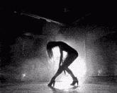 a woman is dancing in a dark room with smoke coming out of the ceiling