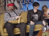 two people are sitting on a couch and one of them is wearing a beret