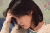 a woman holds her hand to her forehead and looks down