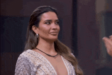 a woman in a plunging neckline dress is waving her hand .