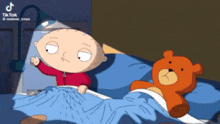 a cartoon of stewie from family guy laying in bed next to a teddy bear