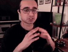 a man wearing glasses and ear buds is looking at the camera .