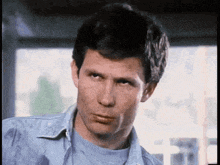 a man in a denim shirt is making a funny face .