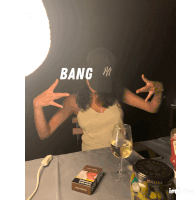 a woman wearing a hat that says bang is sitting at a table