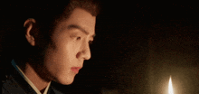 a man is looking at a candle in a dark room .