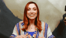a woman with red hair and a striped sweater smiles