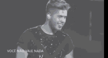 a black and white photo of a man in a sequined shirt with the words você não vale nada below him
