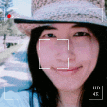 a woman wearing a straw hat is being recorded in hd 4k