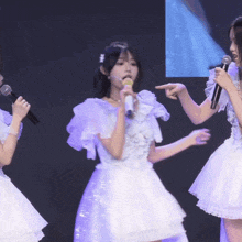 a girl singing into a microphone with another girl pointing