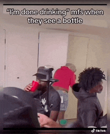 a man is drinking a red cup while another man looks on