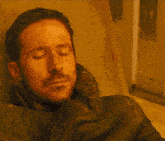 a man with a beard is sitting in a chair and looking at the camera