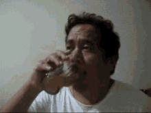 a man in a white shirt is drinking a glass of beer
