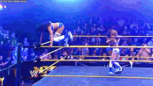 a woman is falling through a wrestling ring while another woman holds her .
